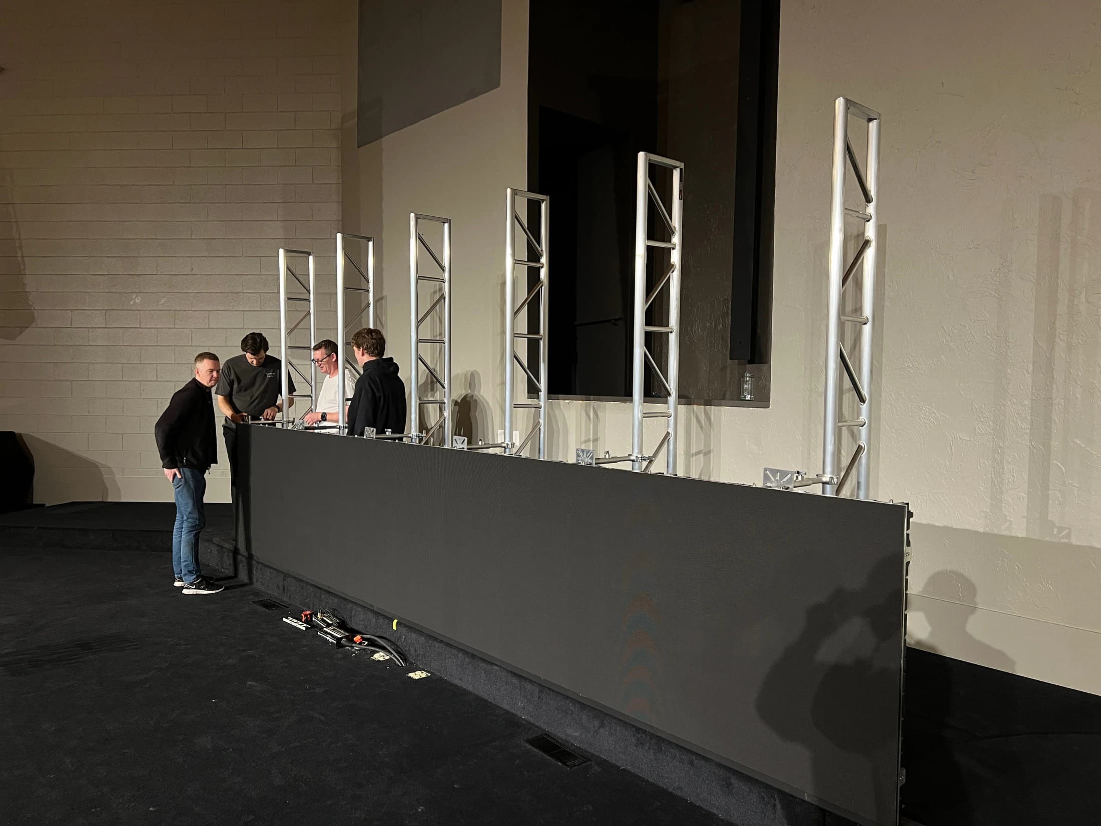 Qohr team assembling the first row of Joy Church LED cabinets against the ground-support uprights