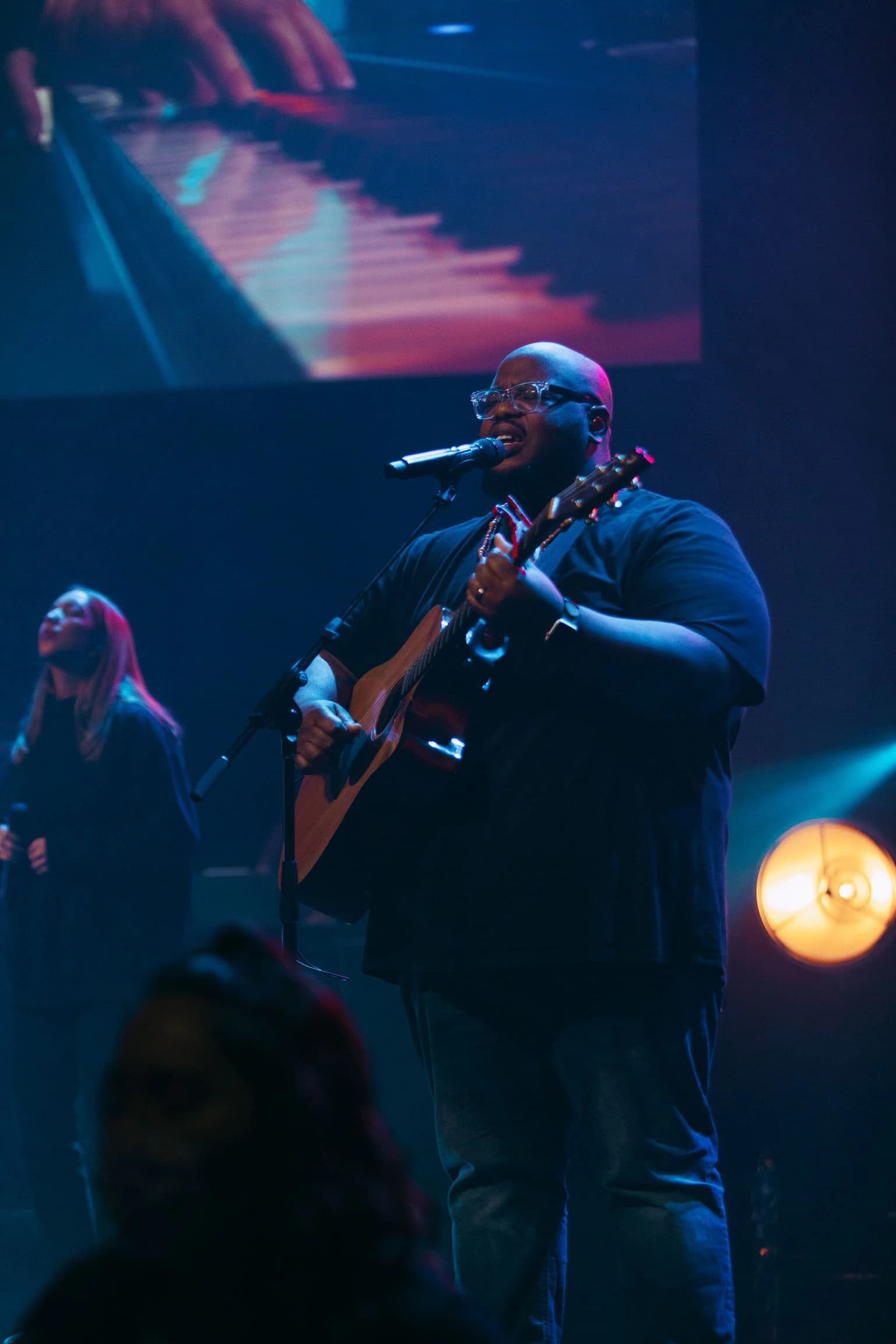 Worship leader performing under church stage lighting