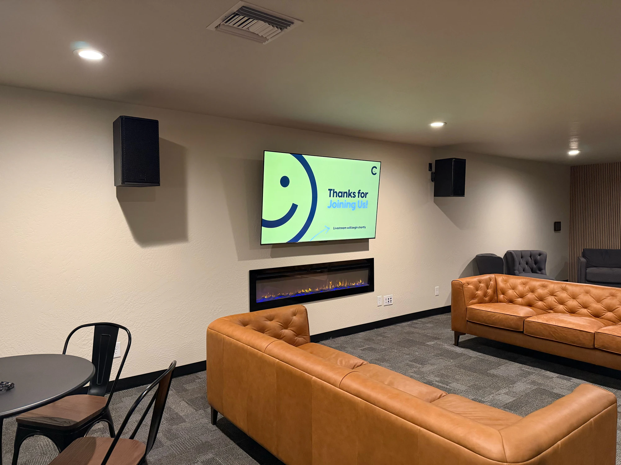 Joy Church lobby with a presentation display, fireplace, seating, and RCF loudspeakers